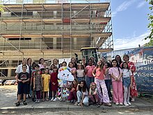 Große Vorfreude auf die neue Schule: Beim Richtfest versammelten sich Kinder und Lehrkräfte vor dem Rohbau des zukünftigen Schulgebäudes und blickten gemeinsam auf die nächsten Baufortschritte.