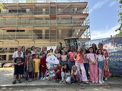 Große Vorfreude auf die neue Schule: Beim Richtfest versammelten sich Kinder und Lehrkräfte vor dem Rohbau des zukünftigen Schulgebäudes und blickten gemeinsam auf die nächsten Baufortschritte.