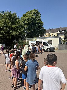 Foto: sehr viele Schüler und Schülerinnen stellen sich am Eiswagen an.