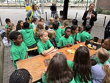 Foto: Kinder schmirgeln ihr Pilgerabzeichen der Wallfahrt mit einer Kokosnussschale.